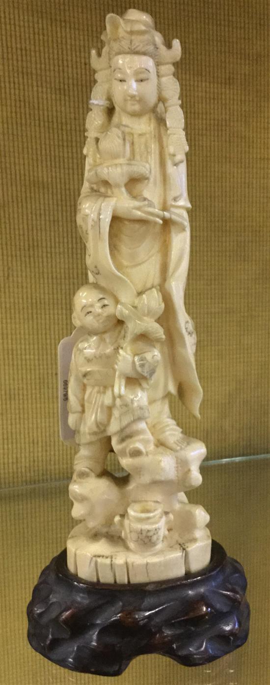 Japanese walrus ivory okimono of Kwannon and a boy, early 20th century wood stand(-)